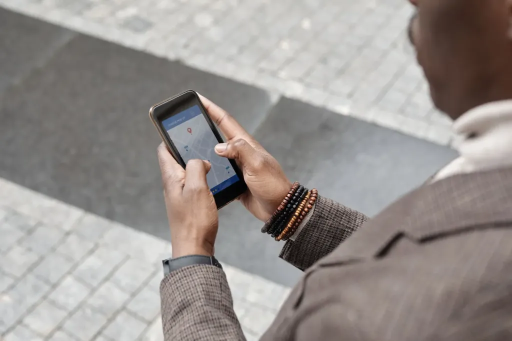 Man in een tweed jasje houdt een smartphone met een kaartapp vast op straat