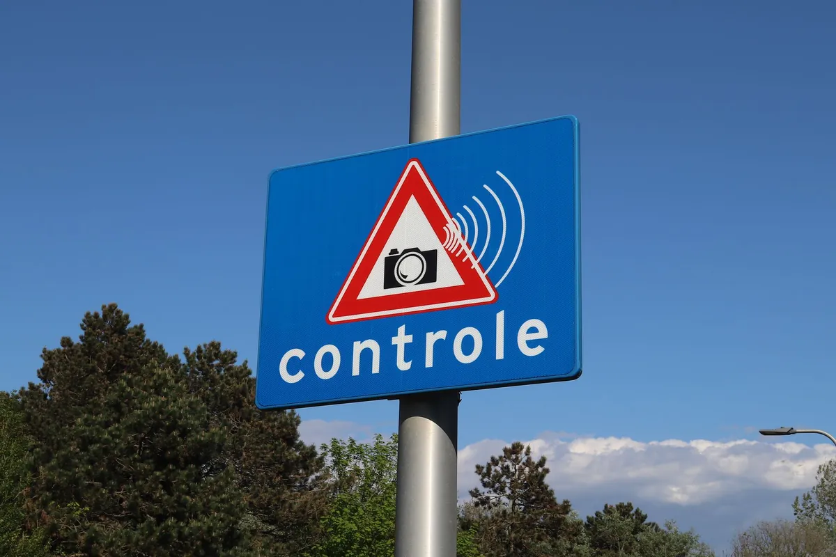 Blauw verkeersbord met camera-symbool en het woord controle langs de weg