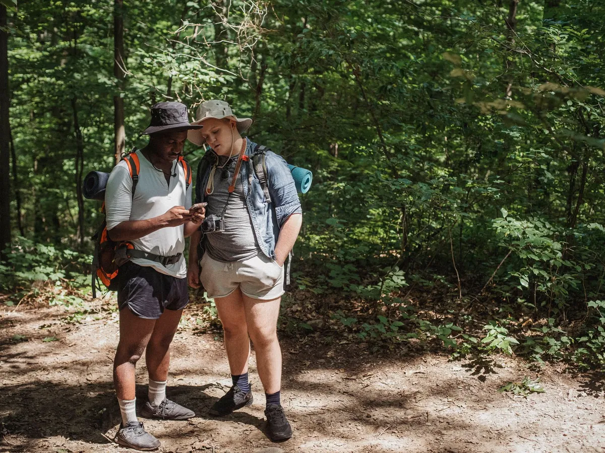 Twee wandelaars in het bos bekijken samen de route op een telefoon
