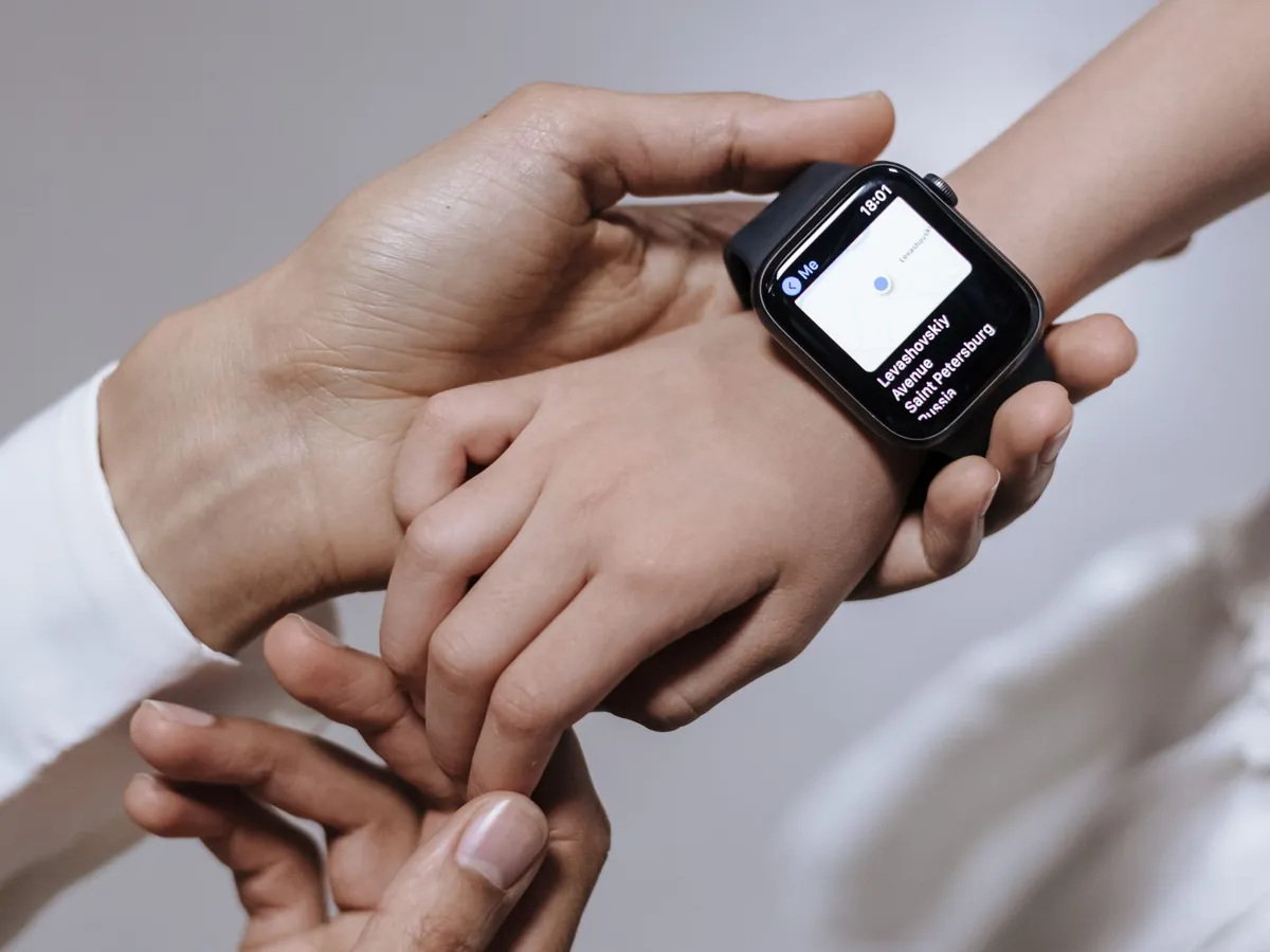 Ouder helpt een kind met een smartwatch om de pols