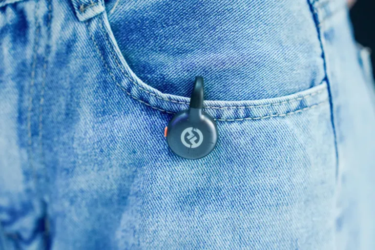 Ronde Bluetooth-tracker aan een sleutelhanger in de zak van een spijkerbroek