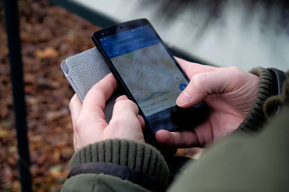 Handen houden een smartphone vast met een kaartapp open in de buitenlucht