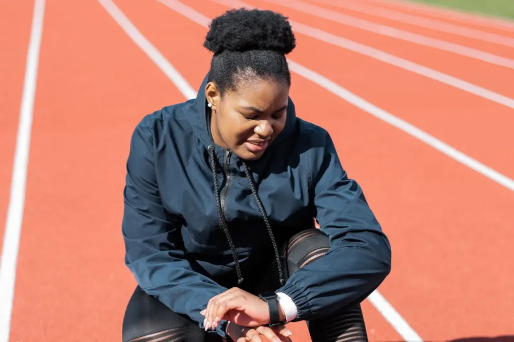 Hardloopster op een atletiekbaan kijkt op haar hardloophorloge voordat ze start