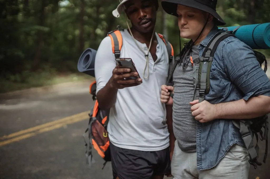 Twee wandelaars met rugzak bekijken samen de route op een smartphone