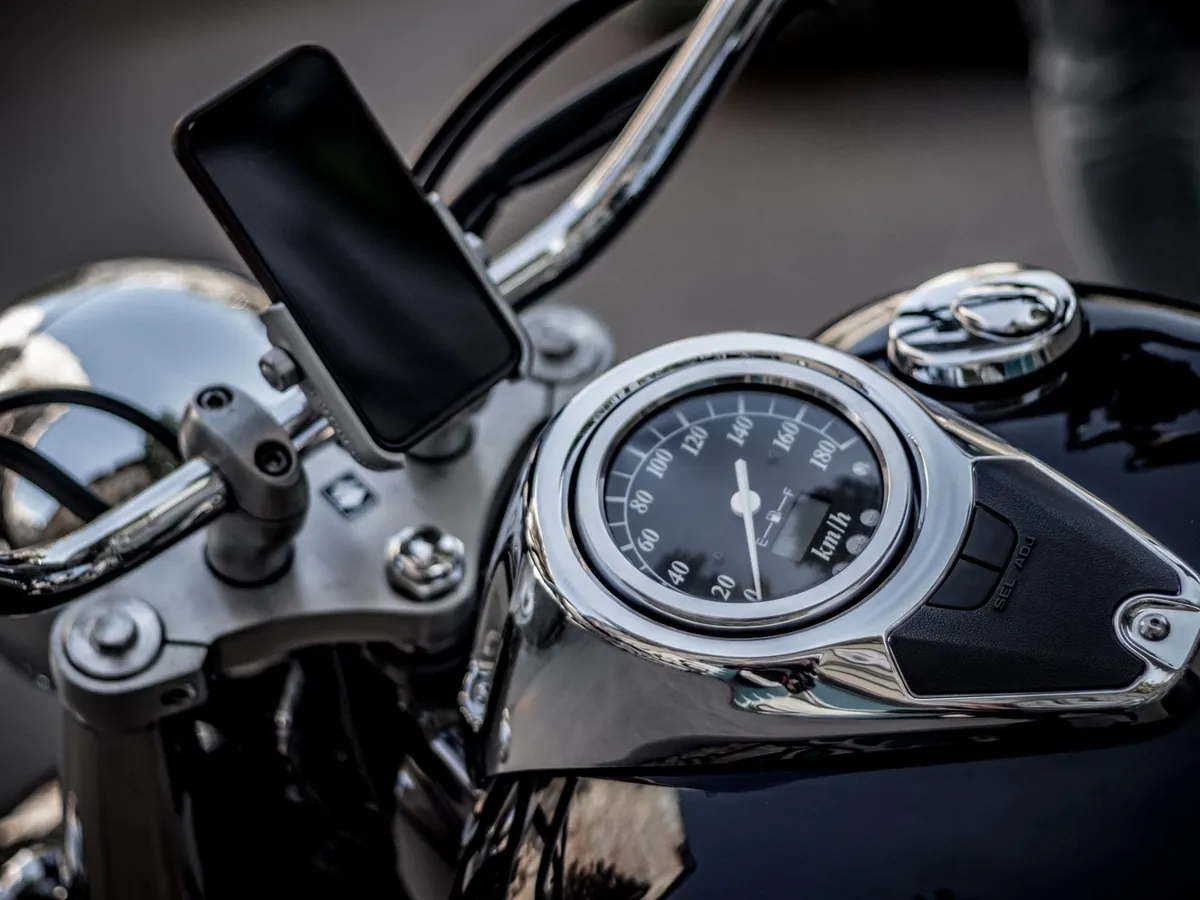 Telefoon in een houder op het stuur van een glimmende motor naast de snelheidsmeter