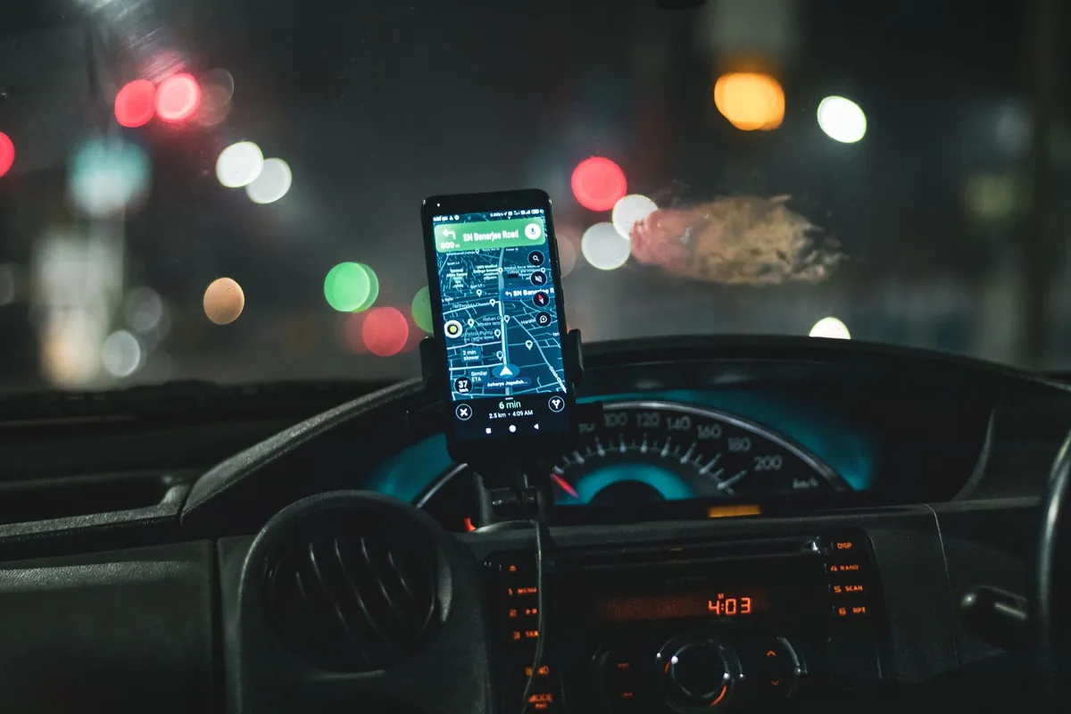 Telefoon met navigatiekaart in de auto tijdens een avondrit met lichten op de achtergrond