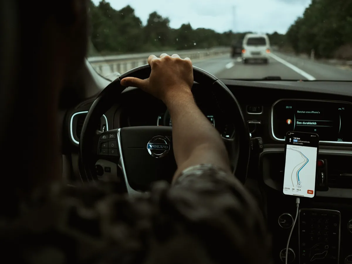 Bestuurder rijdt over de snelweg met een telefoon als navigatiesysteem in een houder